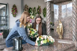 Conseillères funéraires disposant une composition florale sur un monument dans l'espace d'exposition