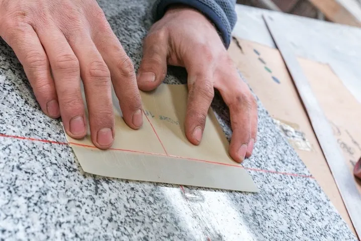 Marbrier préparant un pochoir de gravure sur une plaque funéraire en granit