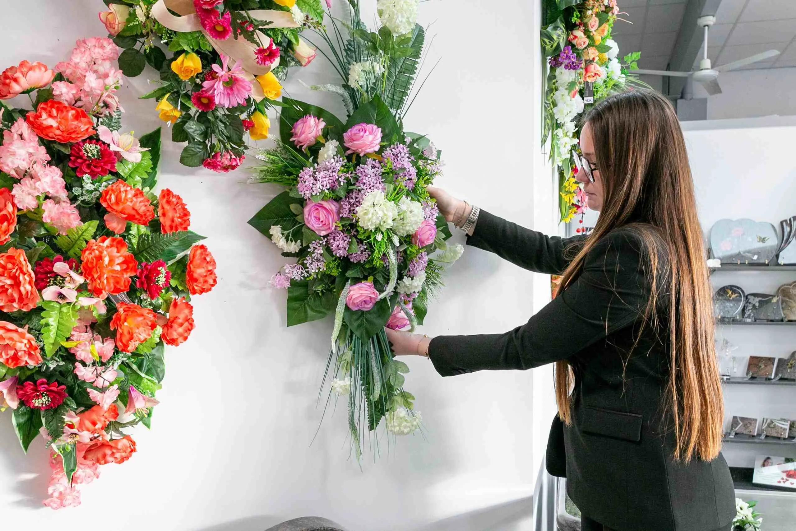 Conseillère funéraire disposant des compositions de fleurs artificielles dans un magasin d'articles funéraires